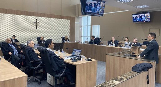 A imagem mostra uma sessão realizada no Pleno do TRE-CE. No centro do espaço há mesas dispostas ...