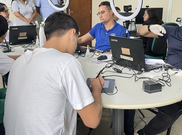 Na imagem também mostra um atendimento. No momento, o jovem está assinando seu nome em um equipa...