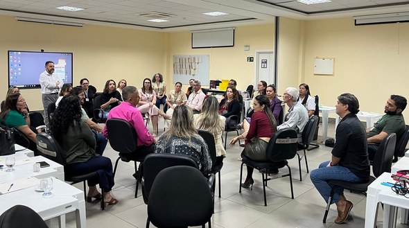Na imagem, as mesmas pessoas estão sentadas em cadeiras dispostas em círculo no centro da sala. ...