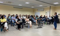 Os alunos da formação estão sentados em cadeiras enfileiradas, olhando para o ministrante, que e...