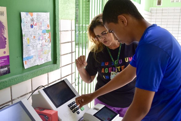 TRE-CE dá início ao projeto “Todo Voto Importa” na Semana da Inclusão e Acessibilidade A quarta imagem mostra um homem em primeiro plano manuseando a urna eletrônica, enquanto uma mul...