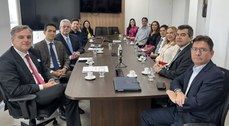 A imagem mostra a reunião na sala da Presidência do TRE-CE. Treze pessoas estão sentadas ao redo...