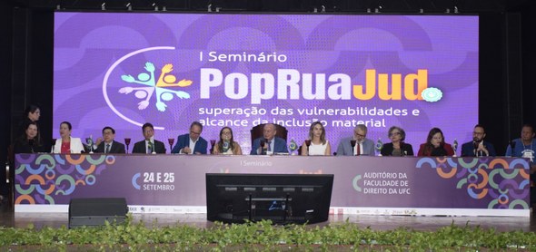 TRE-CE é parceiro na realização do I Seminário PopRuaJud em Fortaleza Na imagem, há mesa de honra, composta por treze pessoas - sete homens e seis mulheres - sentadas...
