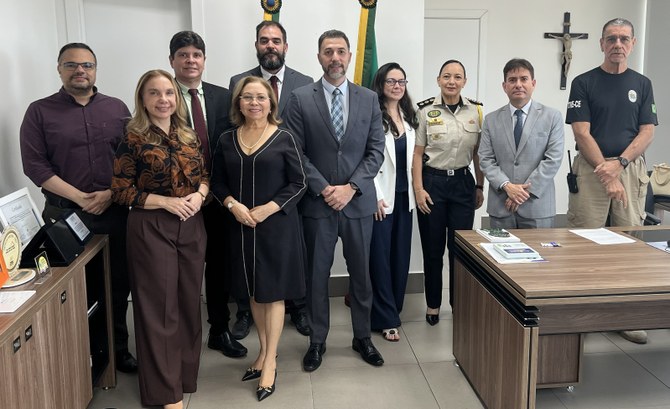 A imagem mostra um grupo de dez pessoas em pé, lado a lado, na sala da Presidência do TRE-CE, po...