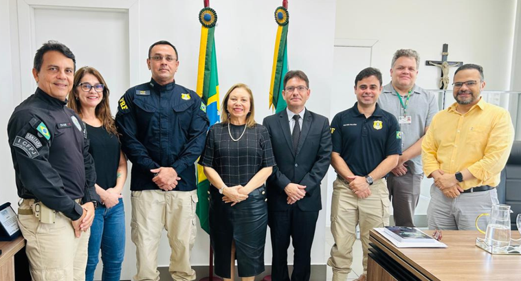 A imagem mostra oito pessoas em pé, alinhadas lado a lado, dentro da sala da Presidência do TRE-...