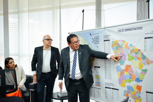 Na foto, o presidente do TRE-CE fala, apontando para um banner, com mapas desenhados. Ao lado de...