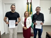 A imagem mostra três pessoas em pé, alinhadas lado a lado, na sala da Presidência do TRE-CE com ...