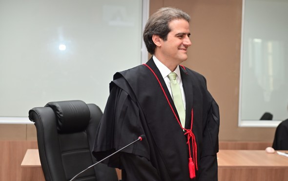 Registro fotográfico feito durante a cerimônia de posse. Nele, o empossado está à frente de uma ...