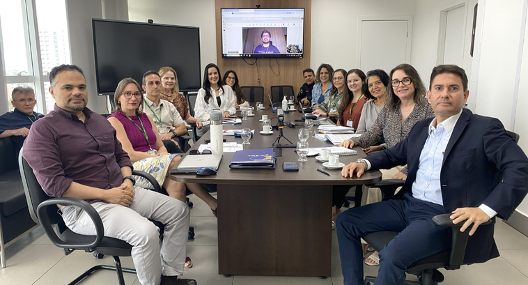 A imagem mostra uma reunião realizada na da Presidência do TRE-CE. Treze pessoas estão reunidas ...