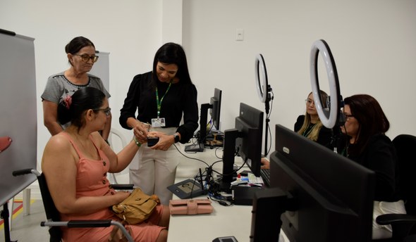 TRE-CE inicia por Santa Quitéria ciclo de inaugurações de novos cartórios eleitorais A imagem mostra um atendimento eleitoral em andamento. A eleitora está sentada em uma cadeira de...