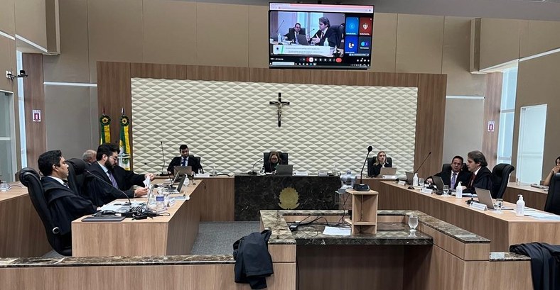 A imagem mostra uma sessão em andamento no Pleno do TRE-CE. A sala possui mesas distribuídas em ...