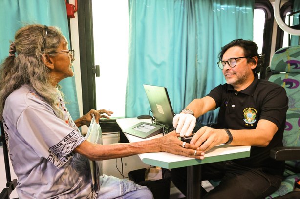 A imagem mostra um atendimento eleitoral em andamento dentro do ônibus do TRE-CE. À esquerda, um...