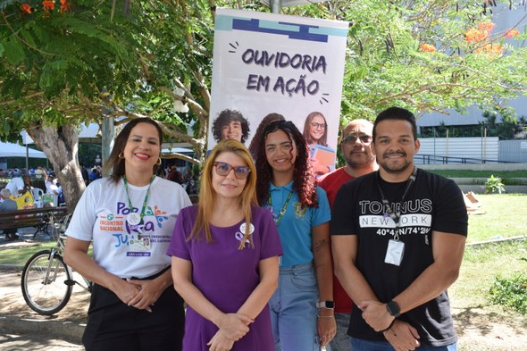 TRE-CE oferece serviços eleitorais em evento alusivo ao Dia de Luta da População em Situação de Rua Na imagem, cinco pessoas - três mulheres e dois homens - posam para a foto, com um banner ao fun...