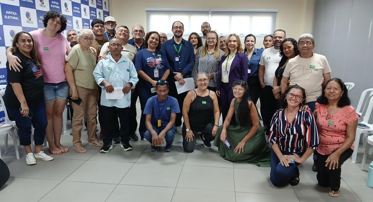 Na imagem, um grupo de pessoas posa para a foto na sala de treinamento do TRE-CE, durante a visi...