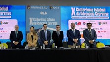 Na primeira imagem, cinco pessoas estão em pé, lado a lado, atrás da mesa principal do evento, v...