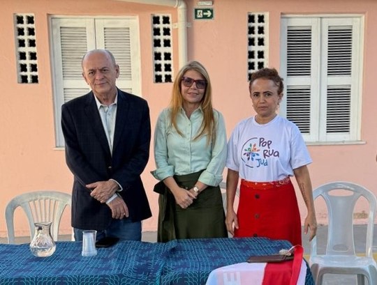 Na imagem, há o registro de uma mesa coberta por uma toalha azul, posicionada em um espaço abert...