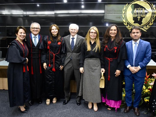 Na imagem, aparecem sete pessoas — quatro mulheres e três homens — posicionadas lado a lado no p...