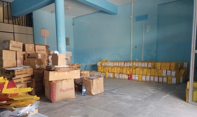 TRE-CE realiza novo descarte ecológico de documentos A imagem é um registro fotográfico. Na cena, um galpão com paredes de cor azul contém diversas p...