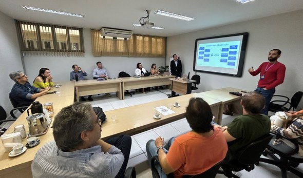 TRE-CE realiza visitas técnicas à Unifor com foco em gestão, inovação e pesquisa aplicada Registro fotográfico feito durante a visita. Nele, dez pessoas estão sentadas ao redor de uma ba...