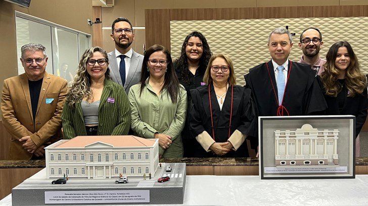 TRE-CE recebe, da UniCatólica, maquetes de sedes antigas para integrar acervo do Centro Memória Eleitoral Na imagem, um grupo de pessoas está posicionado em pé atrás da mesa onde se encontram a maquete ...