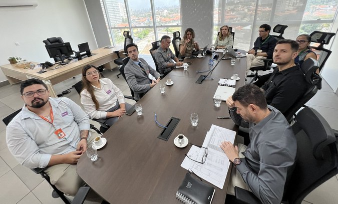 A imagem mostra uma reunião realizada na sala da diretoria-geral na sede do TRE-CE. Dez pessoas ...