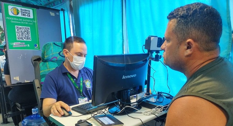 Unidade Móvel do TRE-CE realiza atendimento em Pacatuba nos dias 5 e 6 de setembro A imagem é um registro fotográfico. Nela, um servidor do TRE-CE está à frente de uma mesa com um...